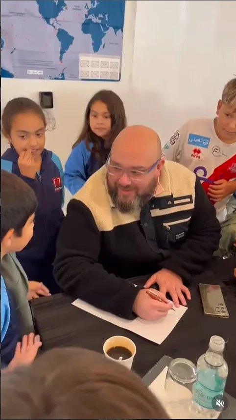 Roberto Aspe firmando libros completamente rodeado de estudiantes entusiastas