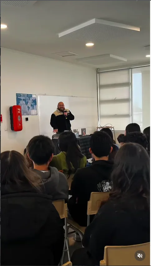 Roberto Aspe con micrófono presentando su obra ante los estudiantes